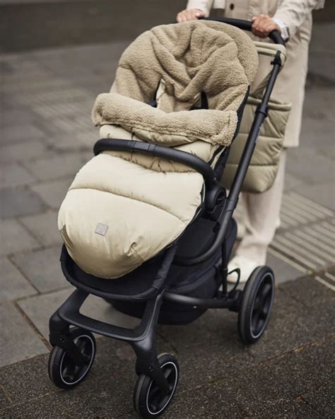 Een baby in een buggy, warm ingepakt in een Jollein voetenzak met teddy voering