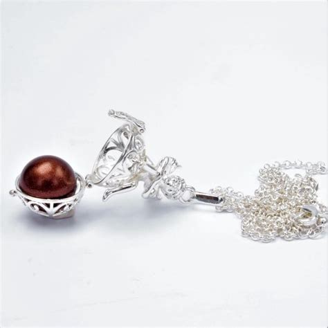 Detailfoto van een zwangerschapsketting (bola) en een selectie van natuurlijke verzorgingsproducten voor zwangere vrouwen.