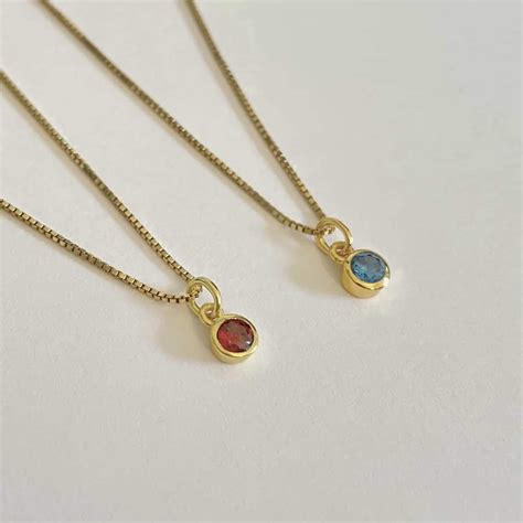 Selectie van elegante sieraden, waaronder een gepersonaliseerde ketting, een ring met geboortesteen en een zwangerschapsbola.