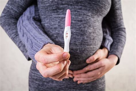 illustratie van een vrouw die een zwangerschapstest vasthoudt met een lichte positieve uitslag