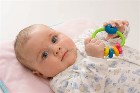Illustratie van een baby die speelt met een rammelaar.