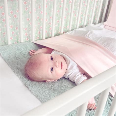 Illustratie van het Nunki lakentje om een matras bevestigd, met een kindje erin dat comfortabel en veilig ligt.