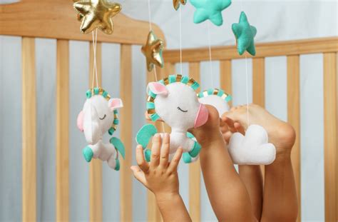 Illustratie van een baby die geconcentreerd speelt met een mobiel boven zijn bedje.