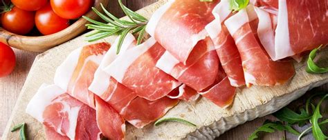 Afbeelding van een Italiaanse markt met diverse soorten ham, waarbij de focus ligt op het visuele contrast tussen rauwe en gekookte ham.
