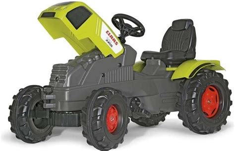 Een kind dat op een rode Rolly Toys traptractor rijdt in een tuin.
