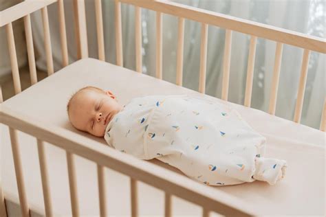 een baby die slaapt in een wiegje met een kruik ernaast