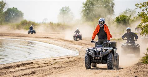 Een groep mensen die quad rijden op een speciaal parcours, met stofwolken achter de quads.