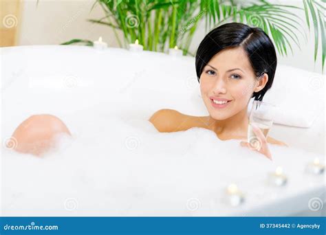 Vrouw die ontspant in een bad, omringd door kaarsen.