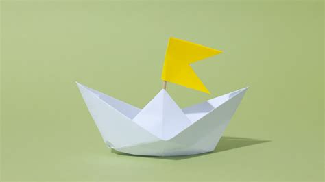 Collage van eenvoudige papieren knutsels: een gevouwen bootje, een geknipte vlinder, een ingekleurde kleurplaat