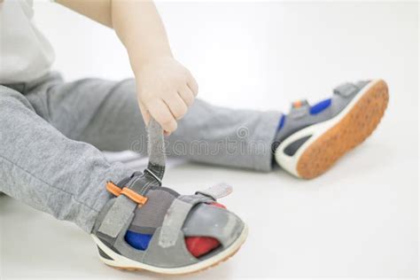 Een peuter die zelfstandig probeert zijn schoenen aan te trekken, met een ouder die geduldig toekijkt.