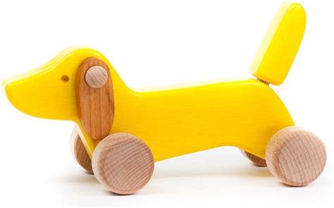 Kind dat een houten teckel speelgoed duwt, focus op de beweging en het kind zijn glimlach.