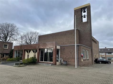 Foto van de Maranathakerk in Lunteren, met de karakteristieke klokkentoren en sobere bakstenen gevels.