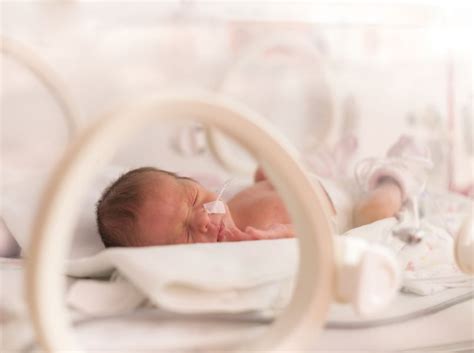 Illustratie van een ouder die een prematuur baby'tje huid-op-huid vasthoudt in een ziekenhuisomgeving.