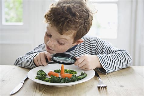 Foto van een kind dat met plezier gezonde groenten eet aan een tafel in de kinderopvang.