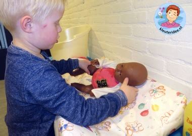 Een jongen die zorgzaam met een babypop speelt.