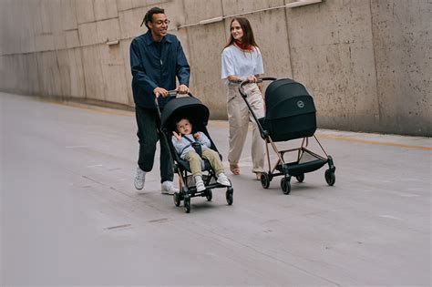 Stadsgezicht met een ouder die een Cybex Priam kinderwagen duwt.