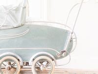 Een overzicht van onderdelen voor antieke kinderwagens, zoals wielen, handgrepen en bekledingsstoffen.