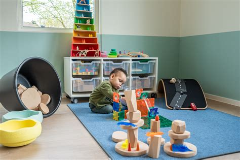 Interieurfoto van een kinderdagverblijf met speelhoeken en natuurlijke materialen.