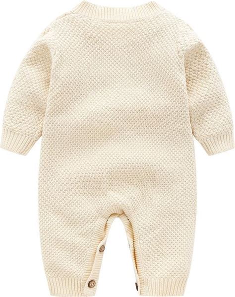 Een close-up van een gebreid baby boxpakje met een knoopsluiting aan de voorkant.