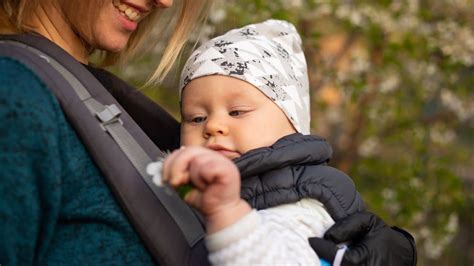 Illustratie van een baby in een draagzak met een wintercover, beschermd tegen de kou.