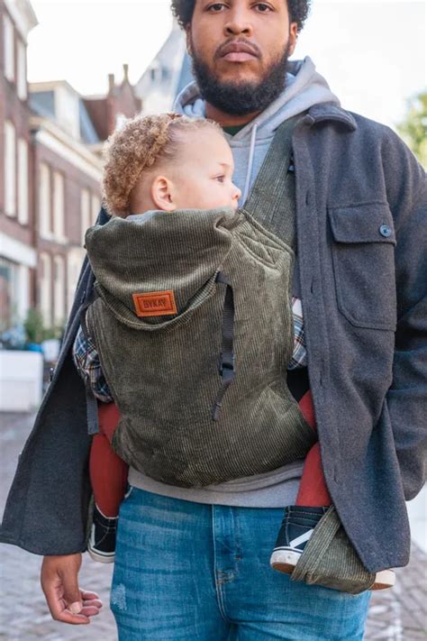 Een ouder die een baby in een ByKay draagzak vasthoudt, met beide handen vrij.