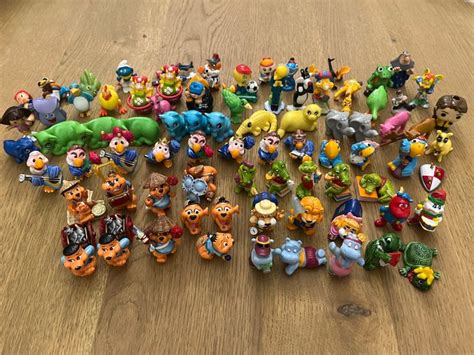 Illustratie van verschillende Kinder Surprise figuren en accessoires.