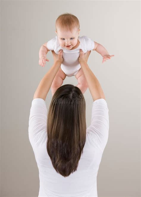 Moeder tilt baby boven haar hoofd, lachend