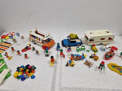 Foto van een verzameling vintage Playmobil speelgoed, waaronder voertuigen en figuren uit de jaren '70 en '80.