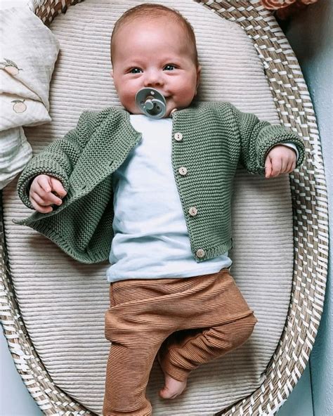 Babykleding jongen collectie met diverse items zoals rompers, broekjes en shirtjes in blauw, grijs en groen.