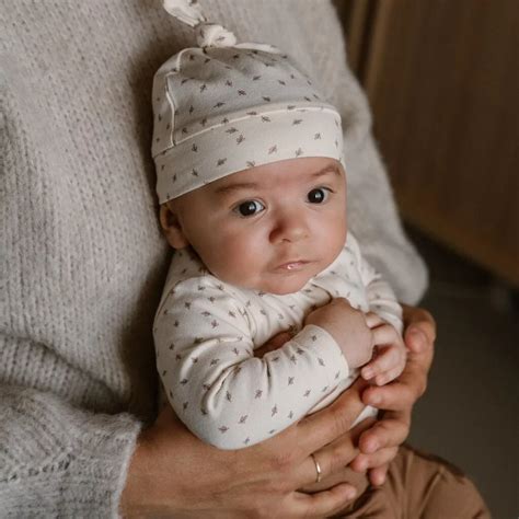Jonge babyjongen in een schattige outfit met romper, broekje en mutsje.