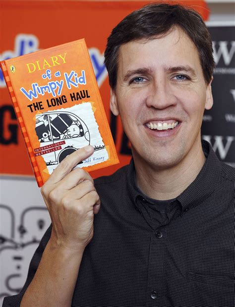 Portretfoto van Jeff Kinney, lachend, met zijn boeken op de achtergrond.